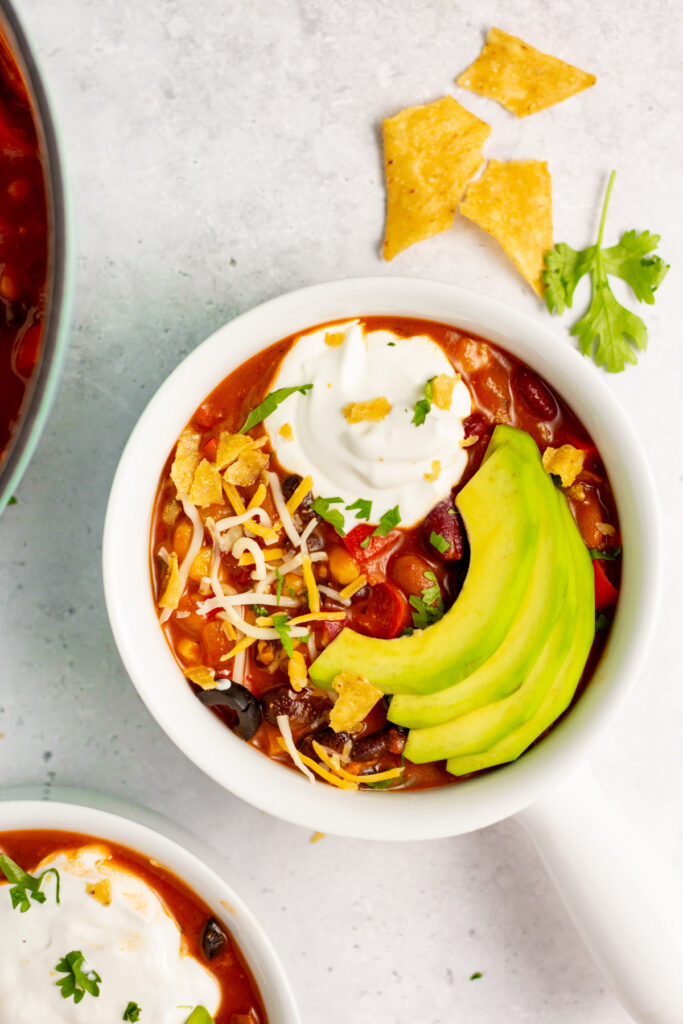 This 3 bean vegetarian chili is a meatless dinner option that’s perfect for meal prep, or a healthy yet filling weeknight meal that’s also dairy-free and gluten-free. It’s incredibly easy to make, only has a 30-minute cook time and is made with pantry staple canned ingredients, so throwing it together on busy days is quick and simple! It’s also a great chili recipe for a chili bar at a family event or football party, because everyone can add their own toppings! #veganchili #beanchili #meatlessrecipes #glutenfree #dairyfreerecipes #slowcookerchili
