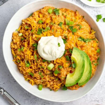 This slow cooker fiesta chicken and rice recipe is a simple weeknight dinner that the whole family will love. You can use this recipe for taco night or burrito night, for an easy meal prep recipe, or for homemade nachos at a family gathering or football party. It's full of flavor, perfectly cheesy, and gets in some vegetables with green peppers and onions. With under 30 minutes of hands-on time and only one dish, you will love this set it and forget it meal! #slowcookerfiestachicken #slowcookerchicken #footballrecipes #burritofilling #crockpotchicken