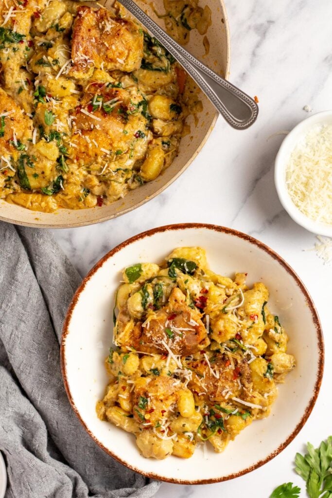 This garlic chicken gnocchi skillet is the perfect simple recipe for a quick weeknight dinner. It's easy, done in 30 minutes, and can be made gluten-free! Juicy chicken thighs and pillowy gnocchi are cooked in a delicious cream sauce, and there's plenty of vegetables included right in the same meal with the spinach, onions and mushrooms. It's truly a one pan wonder that's family friendly, or great for meal prep. #chickengnocchi #glutenfreechicken #weeknightmeals #30minutes #chickenrecipes
