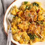 This garlic chicken gnocchi skillet is the perfect simple recipe for a quick weeknight dinner. It's easy, done in 30 minutes, and can be made gluten-free! Juicy chicken thighs and pillowy gnocchi are cooked in a delicious cream sauce, and there's plenty of vegetables included right in the same meal with the spinach, onions and mushrooms. It's truly a one pan wonder that's family friendly, or great for meal prep. #chickengnocchi #glutenfreechicken #weeknightmeals #30minutes #chickenrecipes #chickenskillet