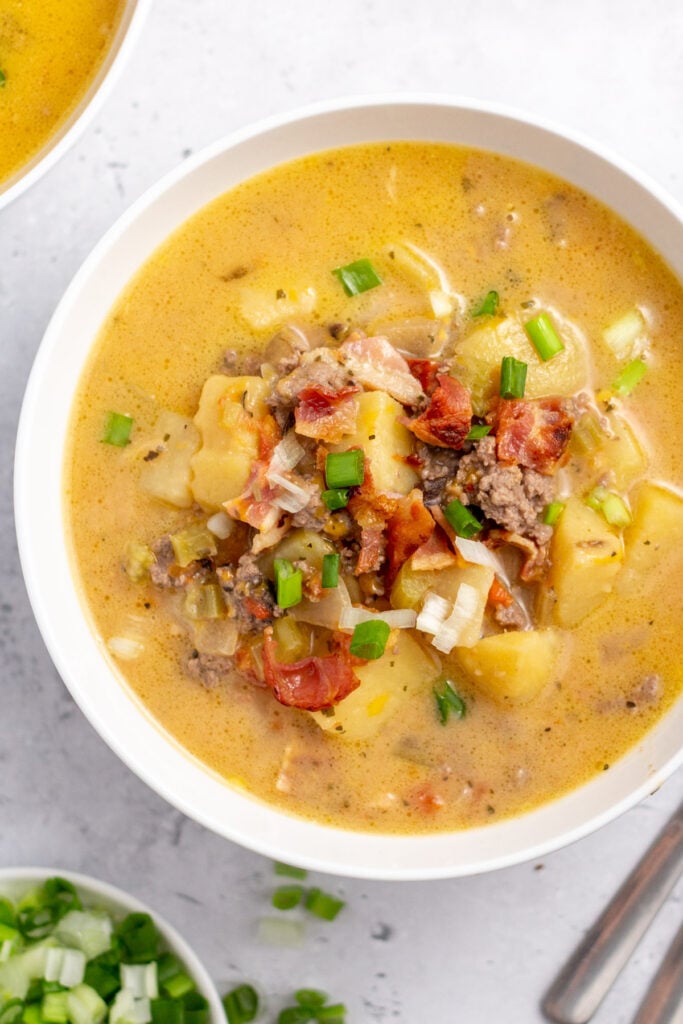 This slow cooker creamy potato bacon soup is going to be a new family-friendly favorite. It's easy to make so it's perfect for a weeknight dinner, and reheats really well so it's great for meal prep. This crock pot ground beef soup is also gluten-free and loaded with vegetables like potatoes, carrots, onion, celery and tomatoes. It's full of flavor and one of our go-to recipes for fall and winter. #slowcookerpotatosoup #potatobaconsoup #groundbeefrecipes #slowcookerbeef #glutenfreesoup
