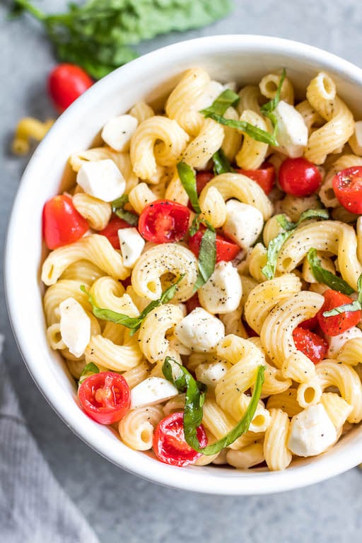 This Caprese pasta salad is bursting with fresh flavors from the cherry tomatoes, basil, mozzarella and oil based dressing. It comes together in 20 minutes, and can be made gluten-free. It's made with very few ingredients and is a perfect side dish to pair with grilled chicken in the summertime or just for meal prep any other time! It's a meatless pasta salad that is a family friendly recipe everyone will fall in love with! #pastasalad #glutenfreepastasalad #capresesalad #tomatorecipes #summersalads