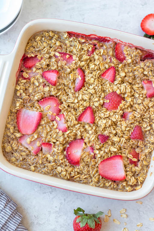 This easy and healthy strawberry baked oatmeal recipe is made with rolled oats, dairy free milk, and the perfect combination of maple syrup and cinnamon! It's totally gluten free, makes great breakfast meal prep, cooks in just 30 minutes, and can be assembled the night before to be baked the next day! #glutenfreebreakfast #breakfastmealprep #dairyfree #strawberryoatmeal #bakedoatmeal